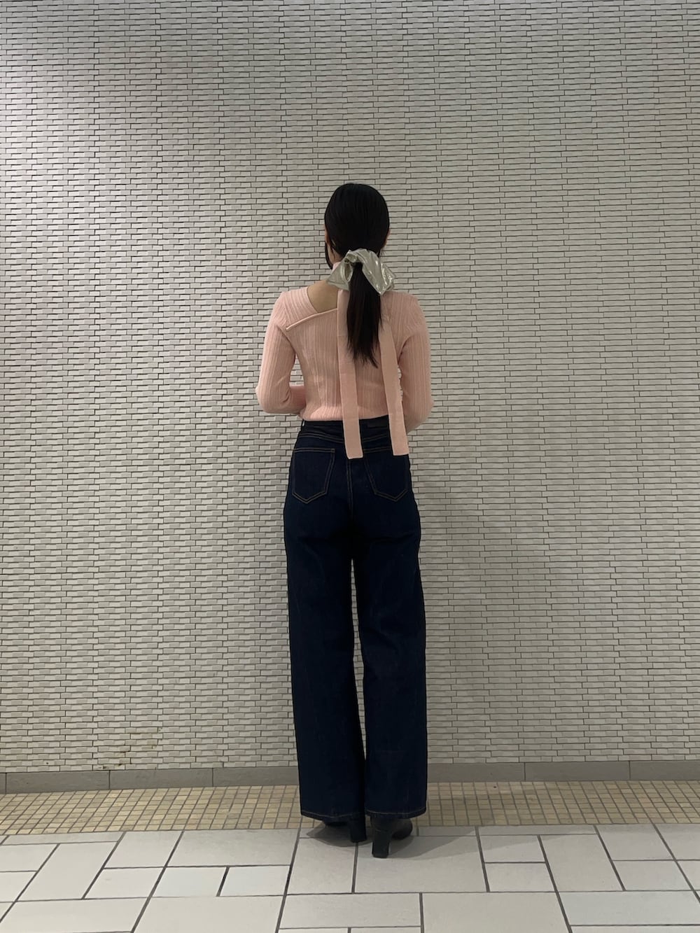 ブルー系のデニムパンツ、ピンク系のニット/セーター、イエロー系のハンドバッグを着用したレディースの冬コーディネートの3枚目の写真