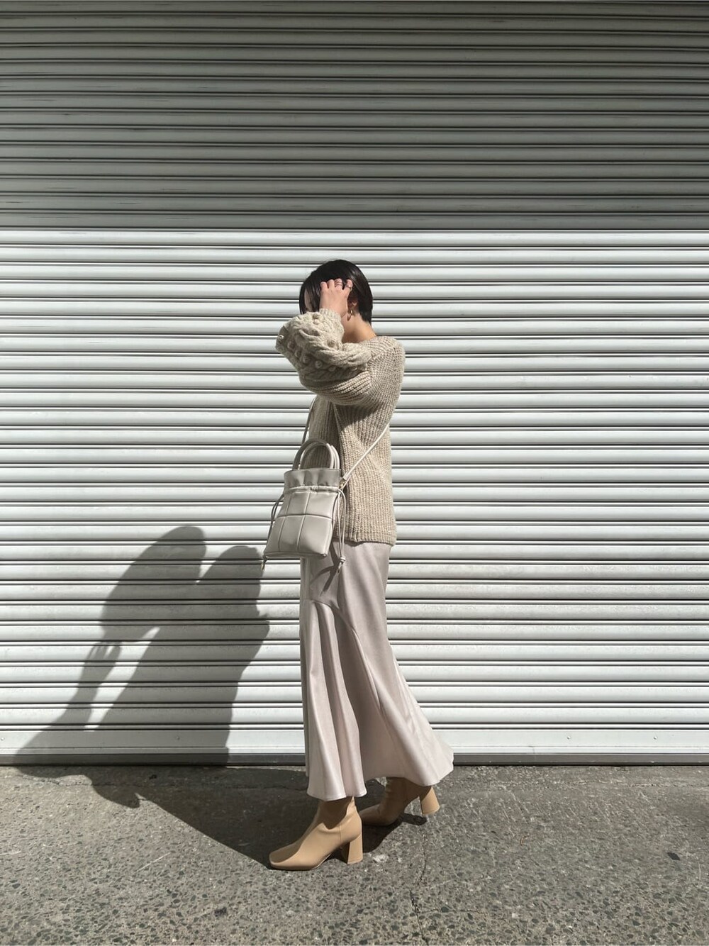 ベージュ系のブーツ、ホワイト系のニット/セーター、グレー系のスカートを着用したレディースの秋コーディネートの2枚目の写真