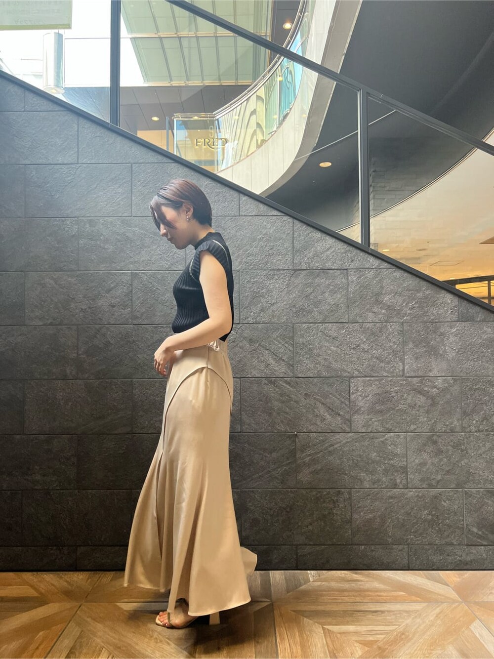 グリーン系のサンダル、ブラック系のニット/セーター、ホワイト系のスカートを着用したレディースの夏コーディネートの4枚目の写真