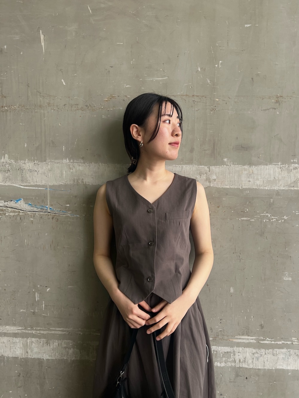 グレー系のワンピース、ブラック系のハンドバッグ、ブラック系のサンダルを着用したレディースの夏コーディネートの3枚目の写真