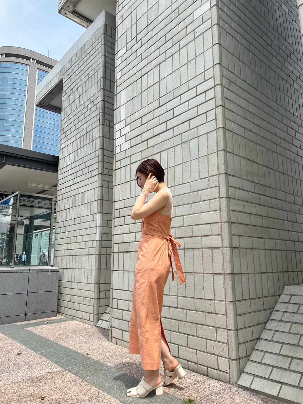 ホワイト系のブルゾン、オレンジ系のワンピース、ホワイト系のサンダルを着用したレディースの春コーディネートの3枚目の写真