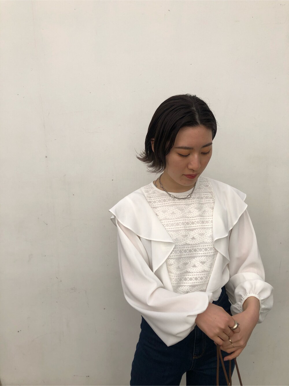 ブルー系のデニムパンツ、ブラック系のハンドバッグ、ブラウン系のパンプスを着用したレディースの春コーディネートの2枚目の写真