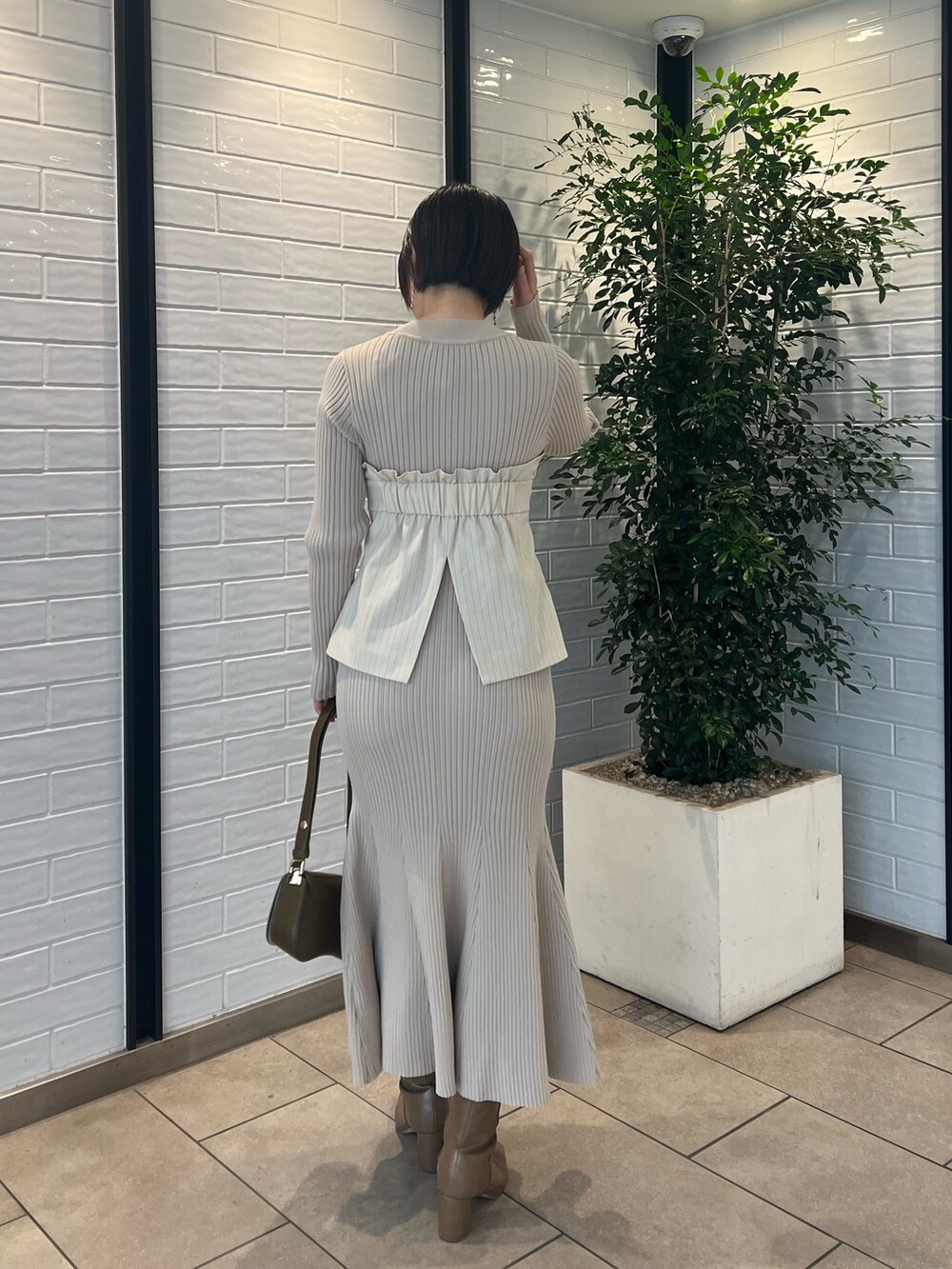 ベージュ系のブーツ、ベージュ系のワンピース、ブラウン系のショルダーバッグを着用したレディースの冬コーディネートの3枚目の写真