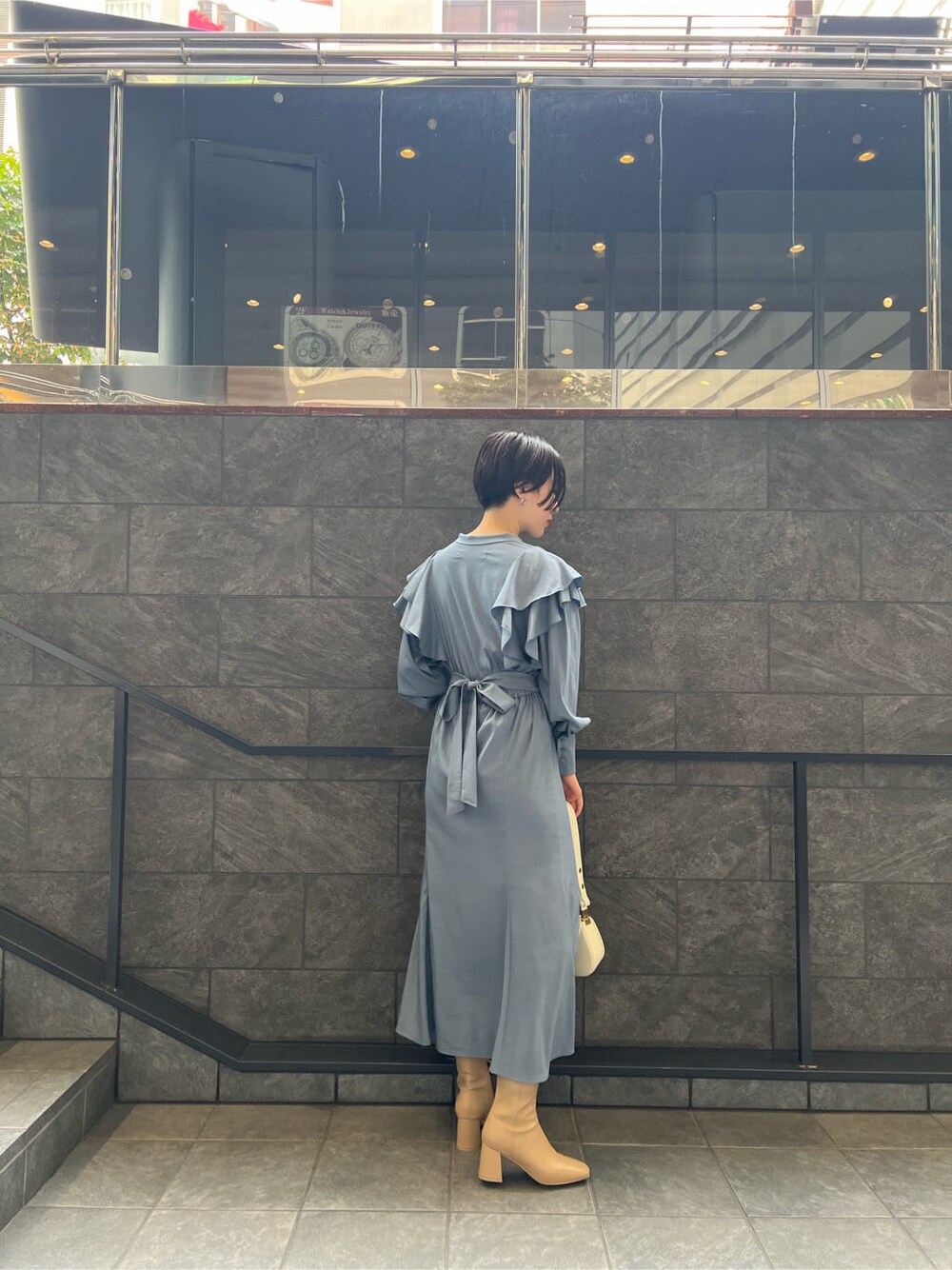 ベージュ系のブーツ、ブルー系のワンピース、ホワイト系のショルダーバッグを着用したレディースの夏コーディネートの3枚目の写真