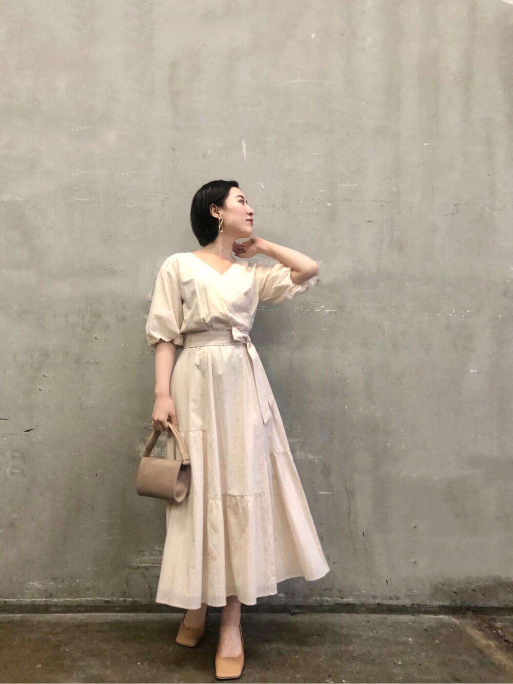 ベージュ系のハンドバッグ、ホワイト系のワンピースを着用したレディースの冬コーディネートの2枚目の写真