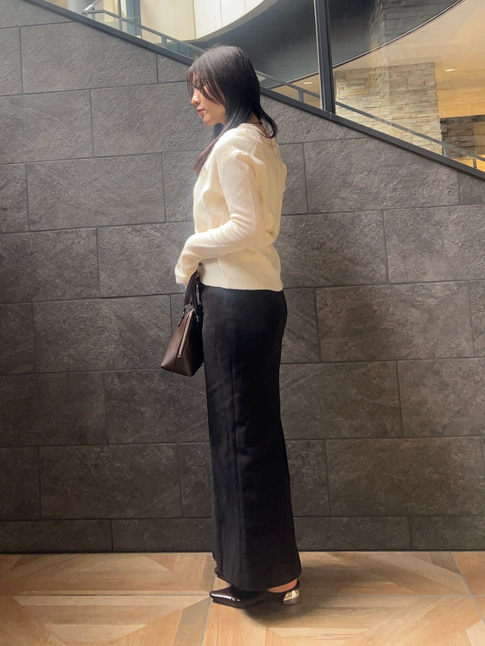 ホワイト系のアンサンブル、ブラック系のスカート、ブラウン系のボストンバッグを着用したレディースの秋コーディネートの2枚目の写真