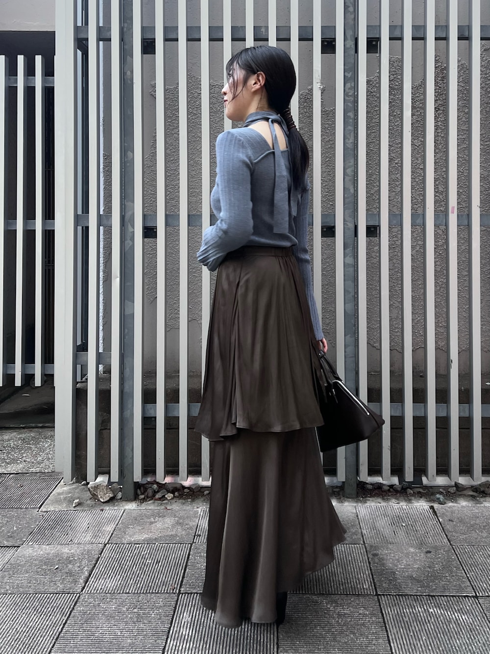 ブルー系のニット/セーター、ブラウン系のスカート、ブラック系のブーツを着用したレディースの秋コーディネートの2枚目の写真