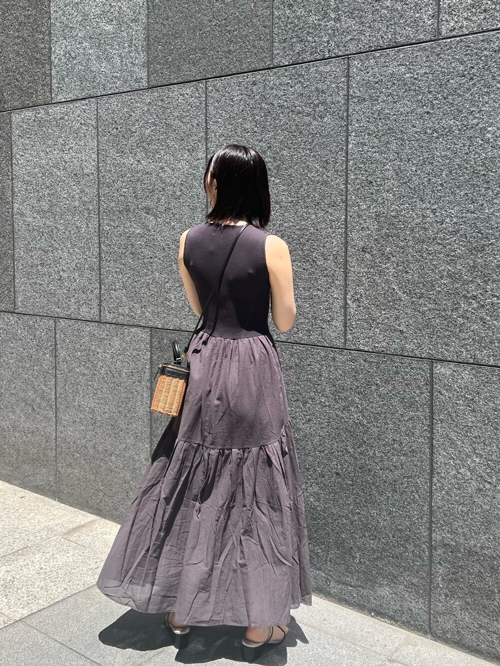 ブラック系のショルダーバッグ、ブラック系のサンダル、グレー系のワンピースを着用したレディースの春コーディネートの2枚目の写真