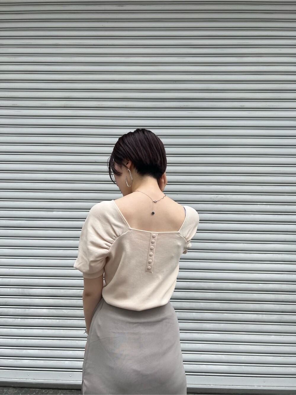 ブラウン系のパンプス、ホワイト系のニット/セーター、ホワイト系のハンドバッグを着用したレディースの夏コーディネートの4枚目の写真