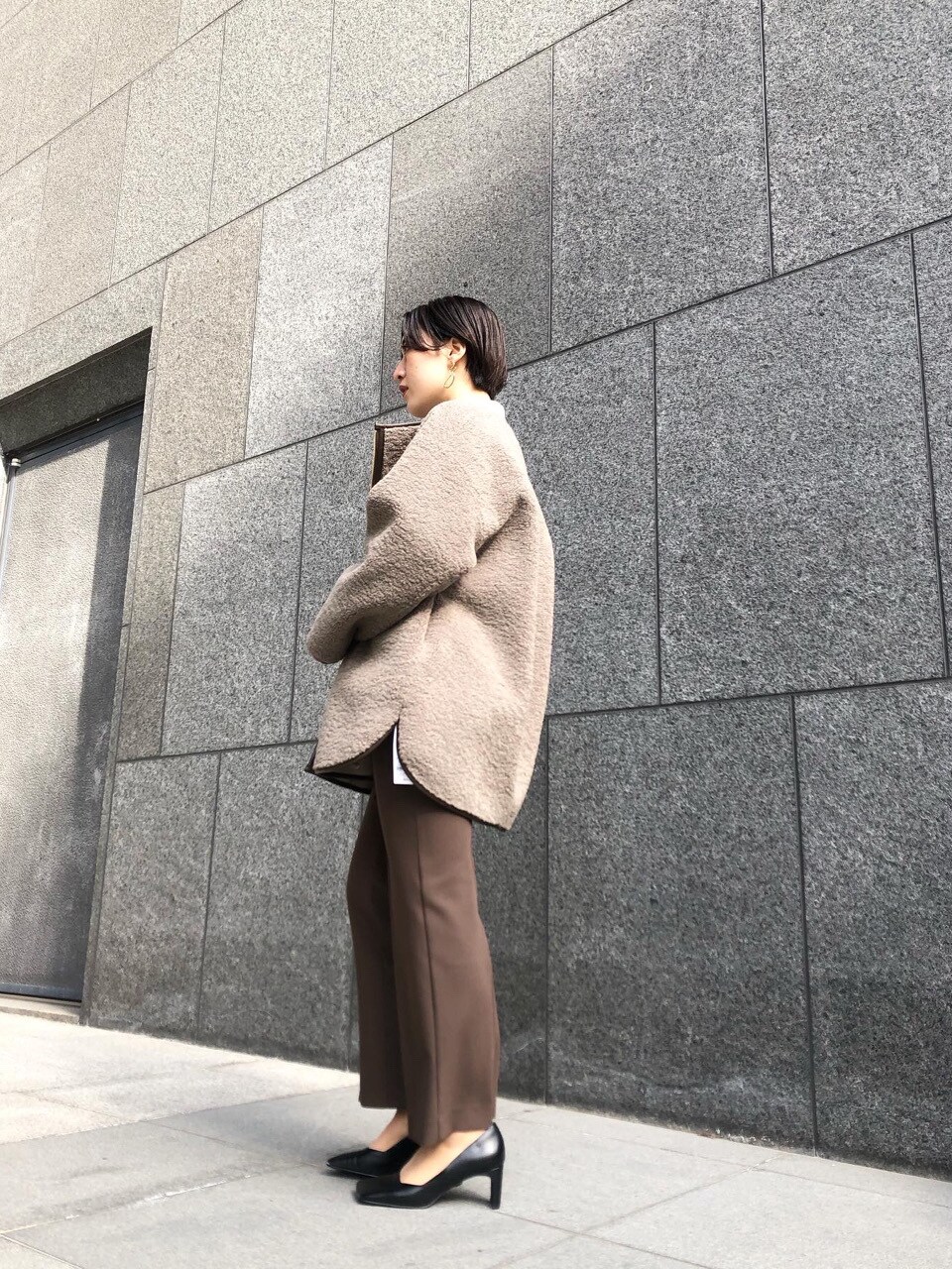 ベージュ系のムートンコート、グレー系のニット/セーター、ゴールド系のピアス（両耳用）を着用したレディースの冬コーディネートの3枚目の写真