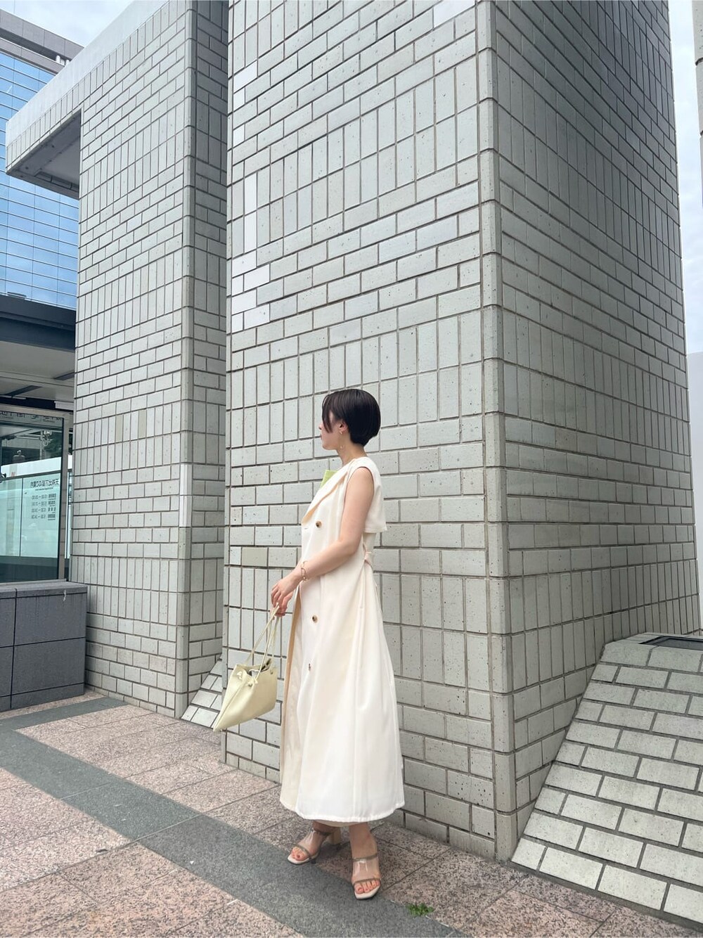 ホワイト系のハンドバッグ、ホワイト系のワンピース、グリーン系のサンダルを着用したレディースの春コーディネートの2枚目の写真