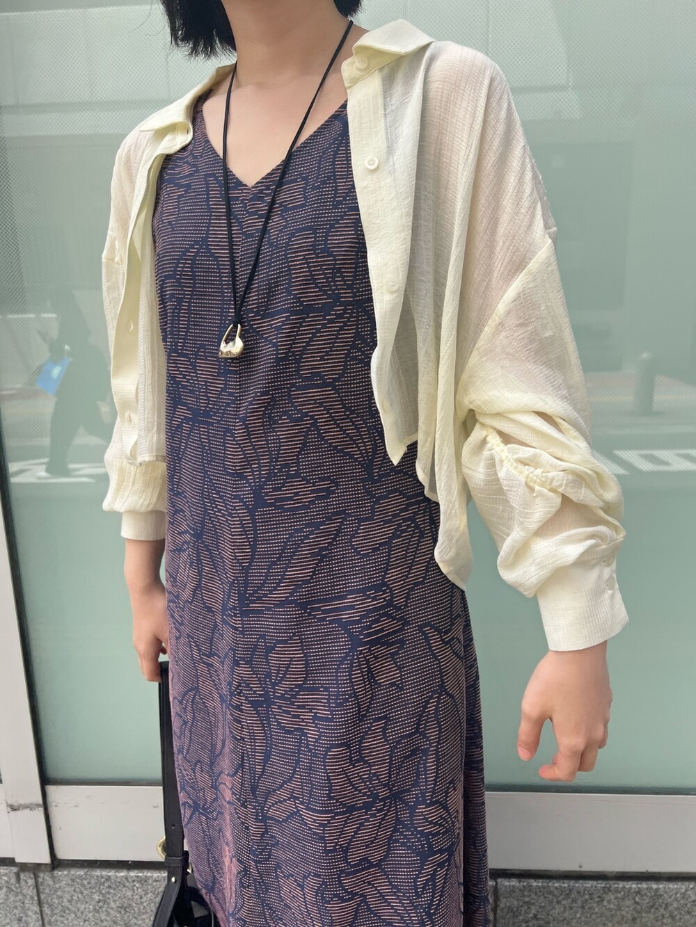 ブラック系のサンダル、ブラック系のワンピース、ホワイト系のシャツ/ブラウスを着用したレディースの春コーディネートの3枚目の写真