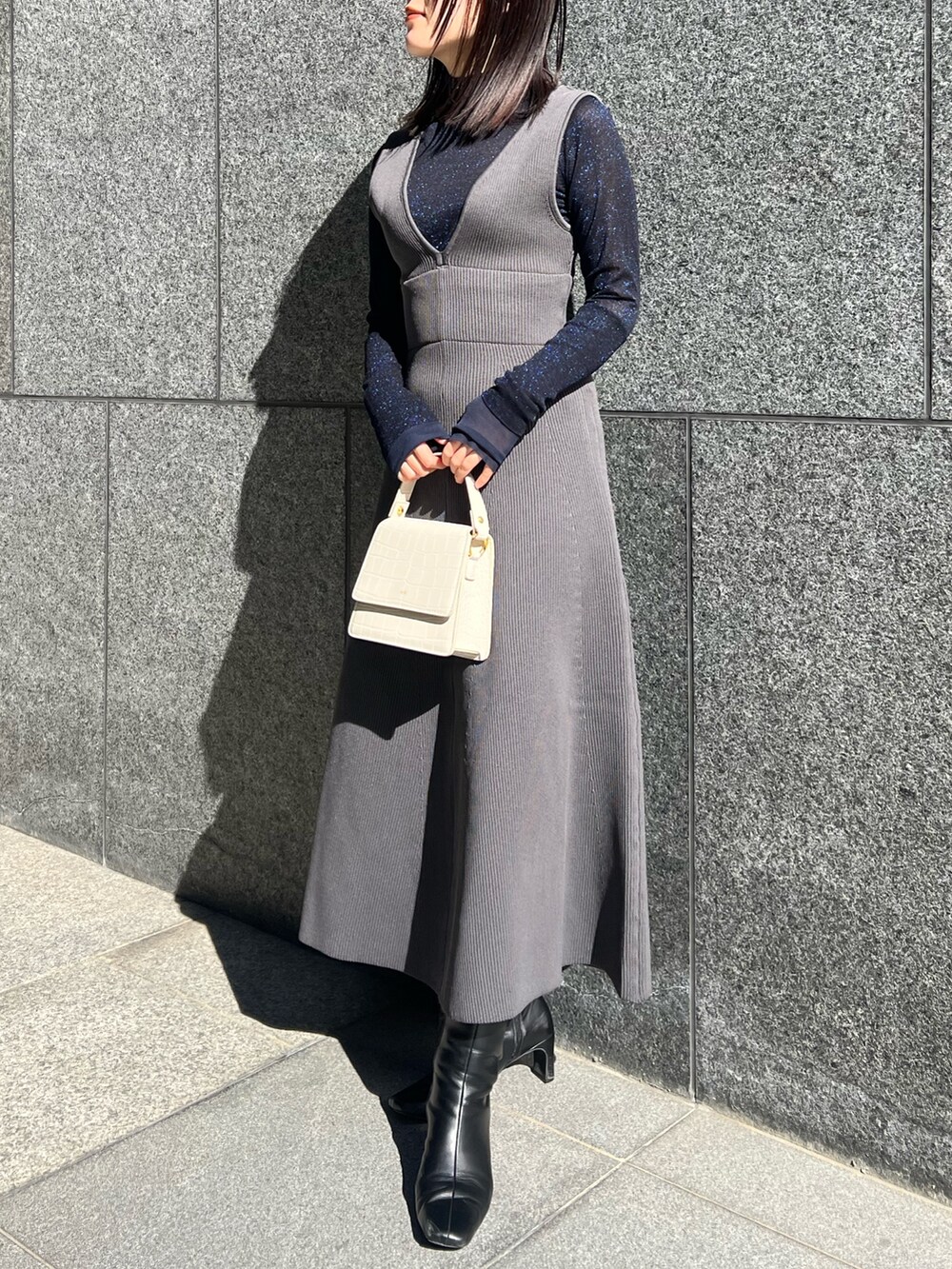 グレー系のTシャツ/カットソー、グレー系のカーディガン/ボレロ、グレー系のジャンパースカートを着用したレディースの秋コーディネートの2枚目の写真