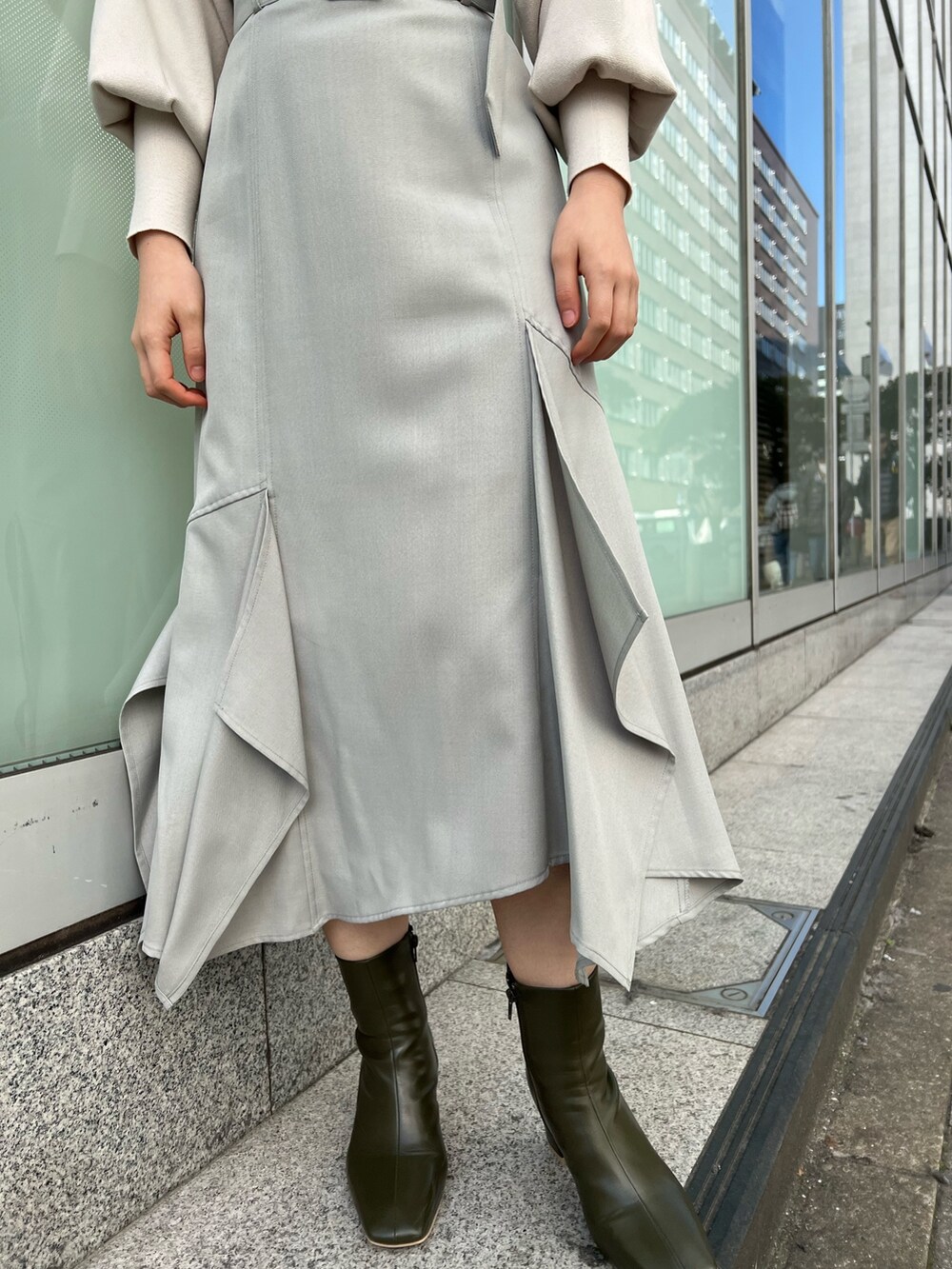 ベージュ系のブーツ、グリーン系のスカート、ホワイト系のニット/セーターを着用したレディースの冬コーディネートの7枚目の写真