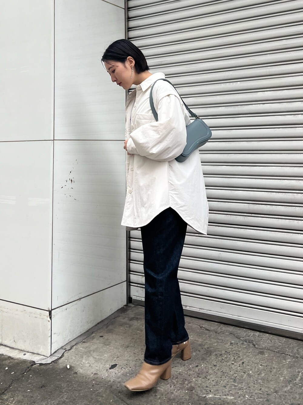 ブルー系のショルダーバッグ、ブルー系のニット/セーター、ベージュ系のブーツを着用したレディースの冬コーディネートの2枚目の写真