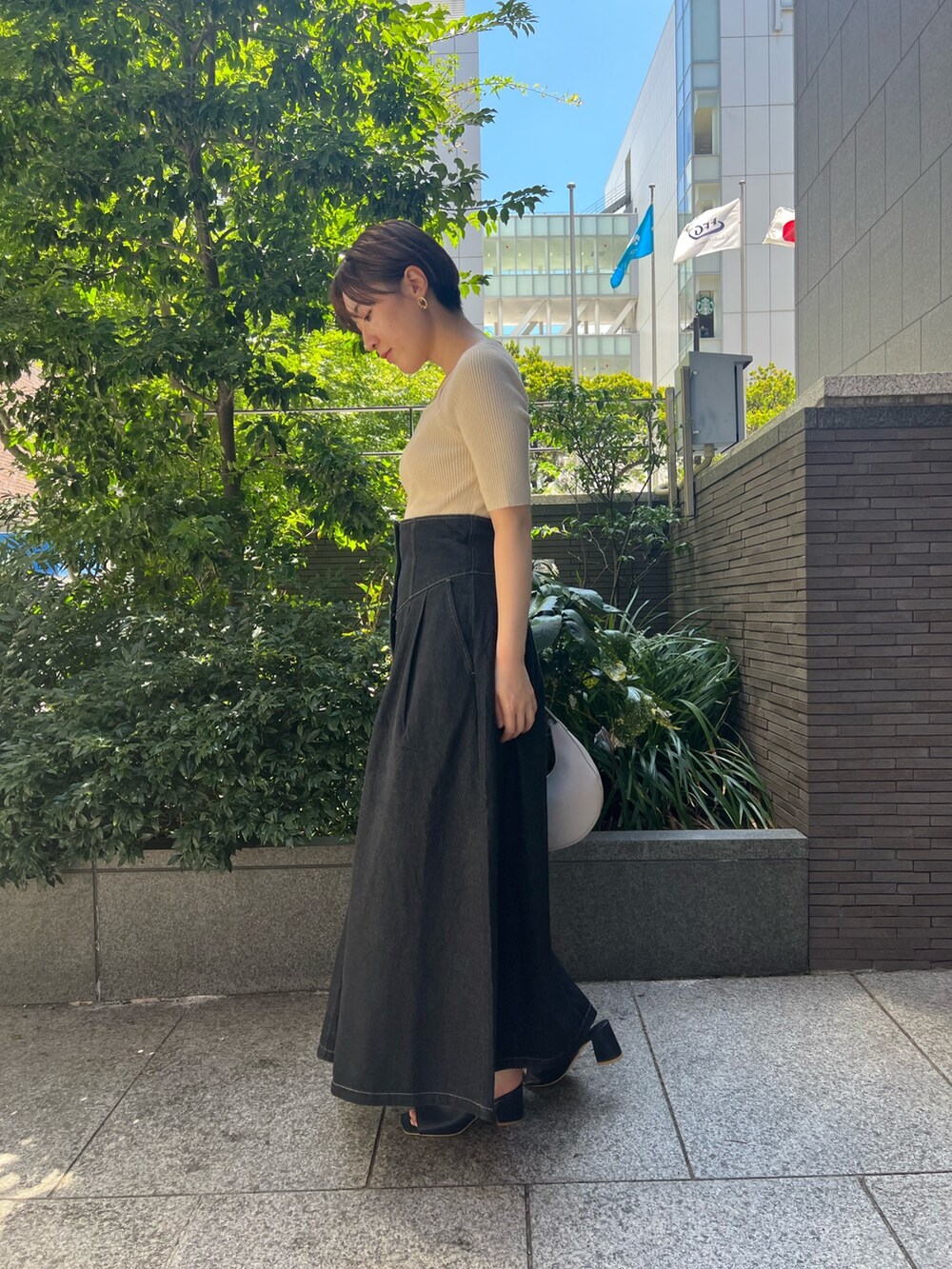 ブラック系のデニムジャケット、ブルー系のニット/セーター、ホワイト系のハンドバッグを着用したレディースの秋コーディネートの7枚目の写真