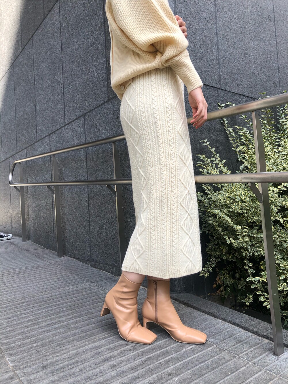 ベージュ系のその他アウター、ピンク系のスカート、ゴールド系のピアス（両耳用）を着用したレディースの冬コーディネートの5枚目の写真