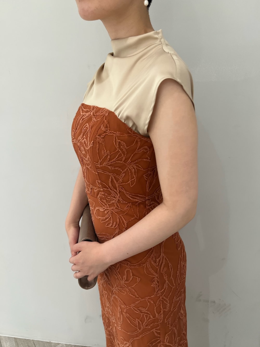 ゴールド系のパンプス、ゴールド系のハンドバッグ、オレンジ系のドレスを着用したレディースの夏コーディネートの4枚目の写真