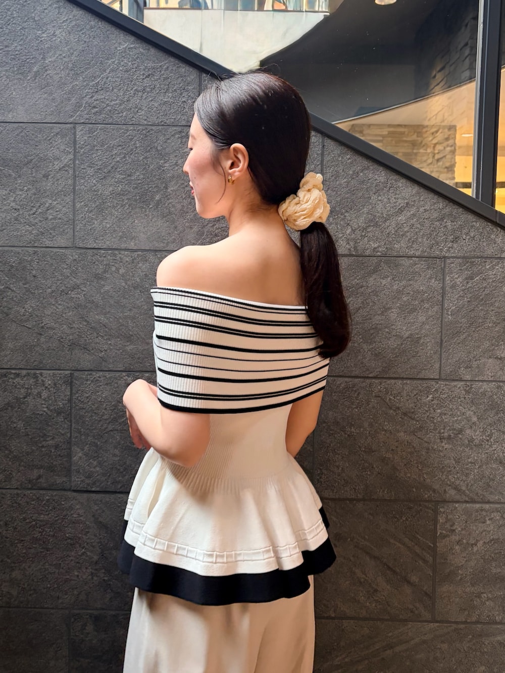 ホワイト系のニット/セーター、ホワイト系のその他パンツ、ブラック系のサンダルを着用したレディースの夏コーディネートの5枚目の写真