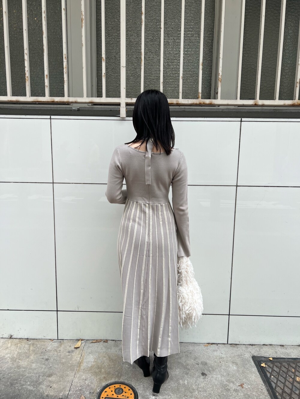 ホワイト系のブルゾン、グレー系のワンピース、ホワイト系のハンドバッグを着用したレディースの冬コーディネートの8枚目の写真