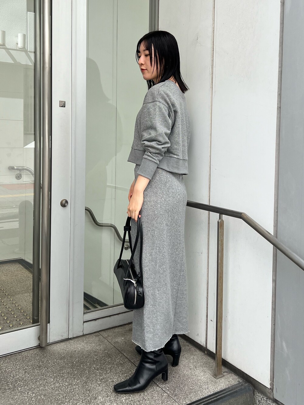 ブラック系のブーツ、グレー系のスカート、グレー系のスウェットを着用したレディースの秋コーディネートの2枚目の写真