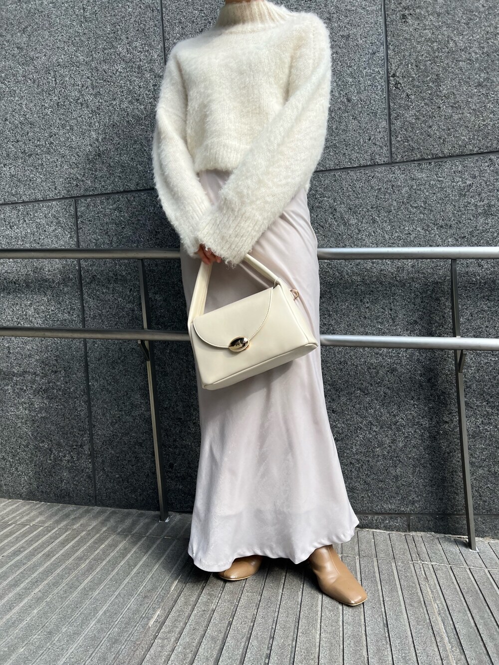 ホワイト系のスカート、ホワイト系のハンドバッグ、ピンク系のカーディガン/ボレロを着用したレディースの冬コーディネートの8枚目の写真