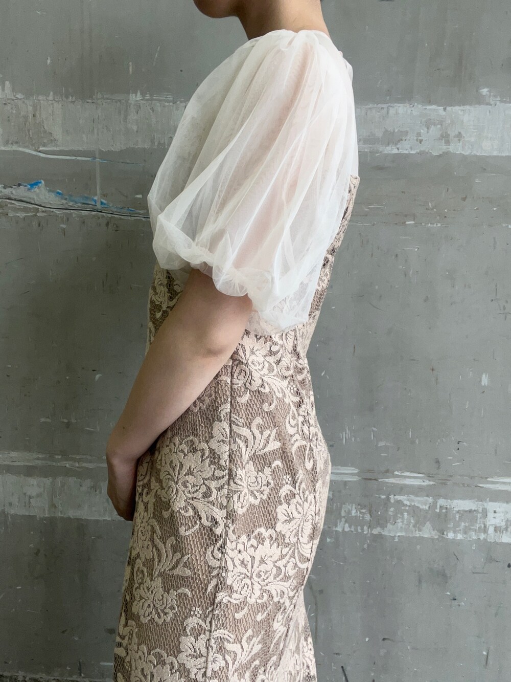 ベージュ系のドレス、ブラウン系のクラッチバッグ、ゴールド系のパンプスを着用したレディースの秋コーディネートの6枚目の写真