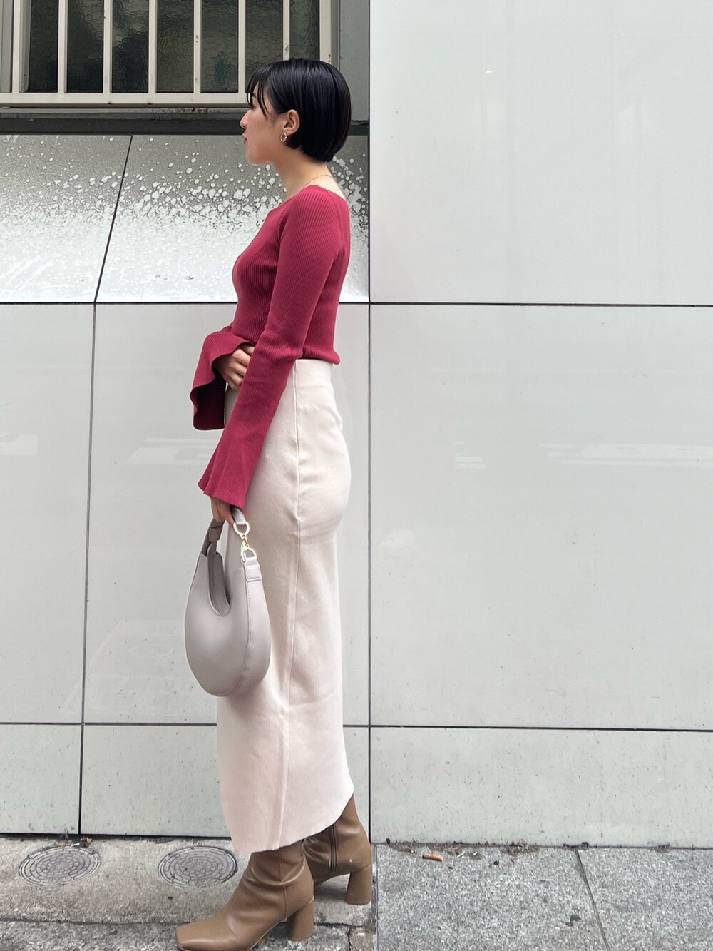 グレー系のノーカラーコート、ベージュ系のブーツ、ホワイト系のハンドバッグを着用したレディースの冬コーディネートの4枚目の写真