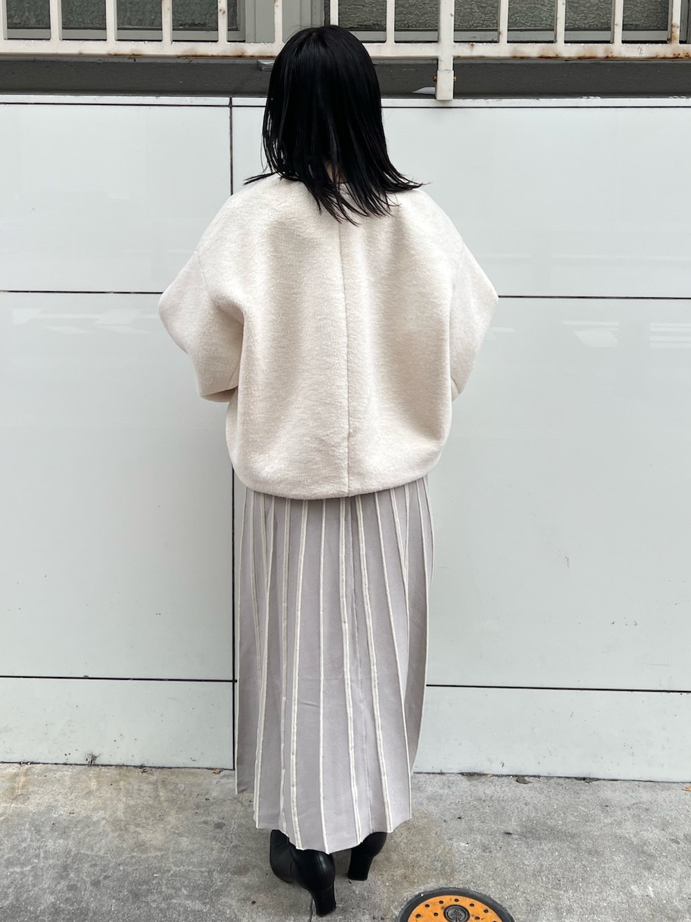 ホワイト系のブルゾン、グレー系のワンピース、ホワイト系のハンドバッグを着用したレディースの冬コーディネートの3枚目の写真