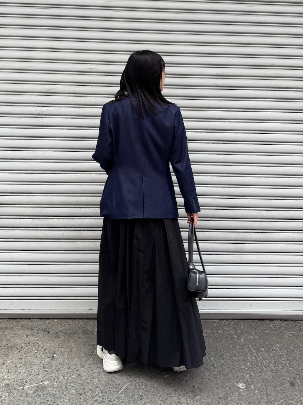 ブラック系のワンピース、ブルー系のテーラードジャケット、グレー系のスニーカーを着用したレディースの冬コーディネートの2枚目の写真