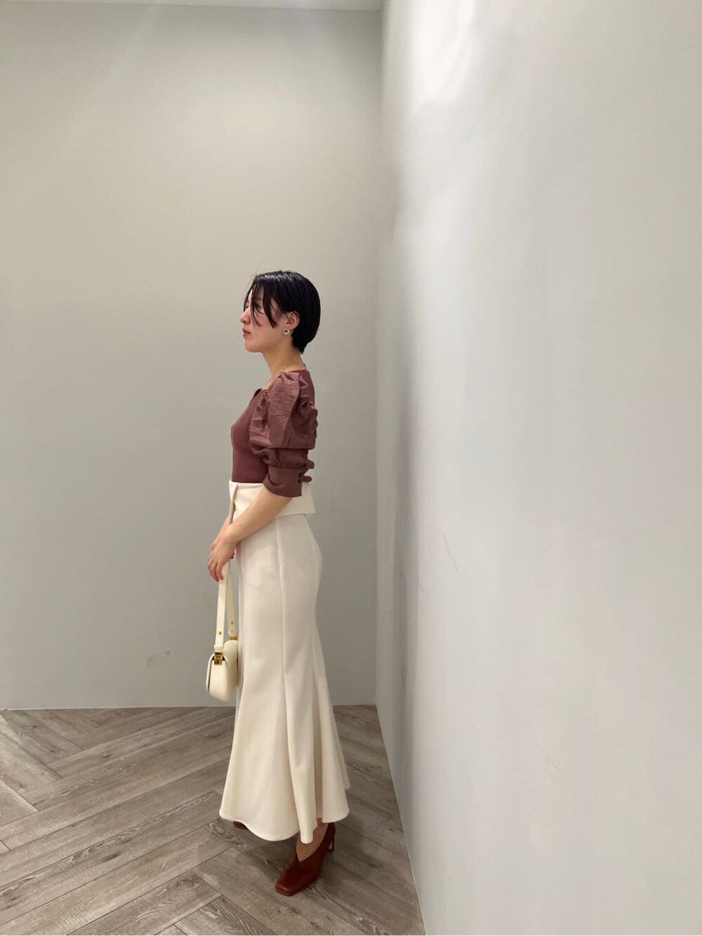 ブラウン系のパンプス、ホワイト系のスカート、ブラウン系のニット/セーターを着用したレディースの夏コーディネートの2枚目の写真