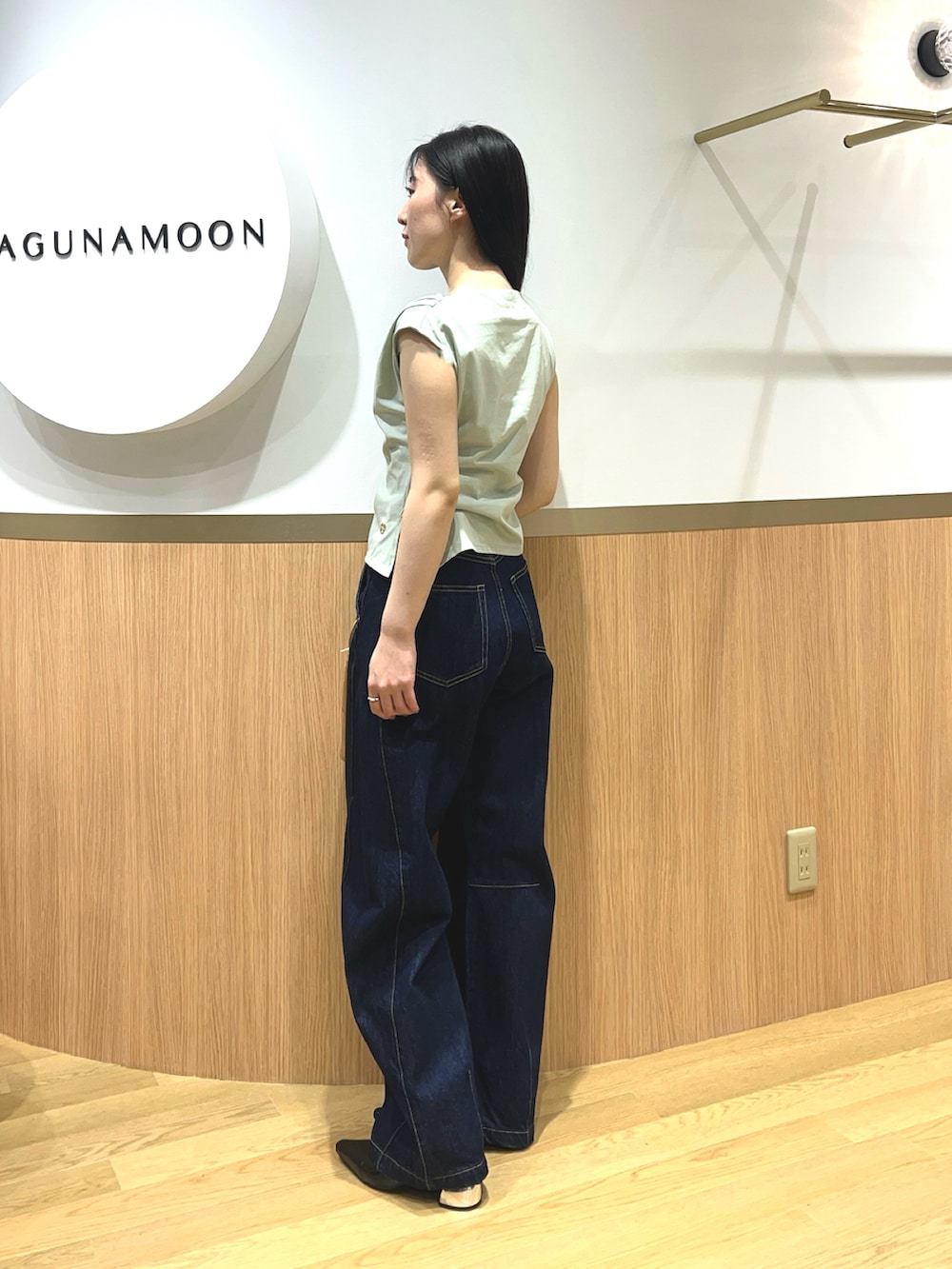 グリーン系のTシャツ/カットソー、ブルー系のデニムパンツ、ブラック系のパンプスを着用したレディースの春コーディネートの2枚目の写真