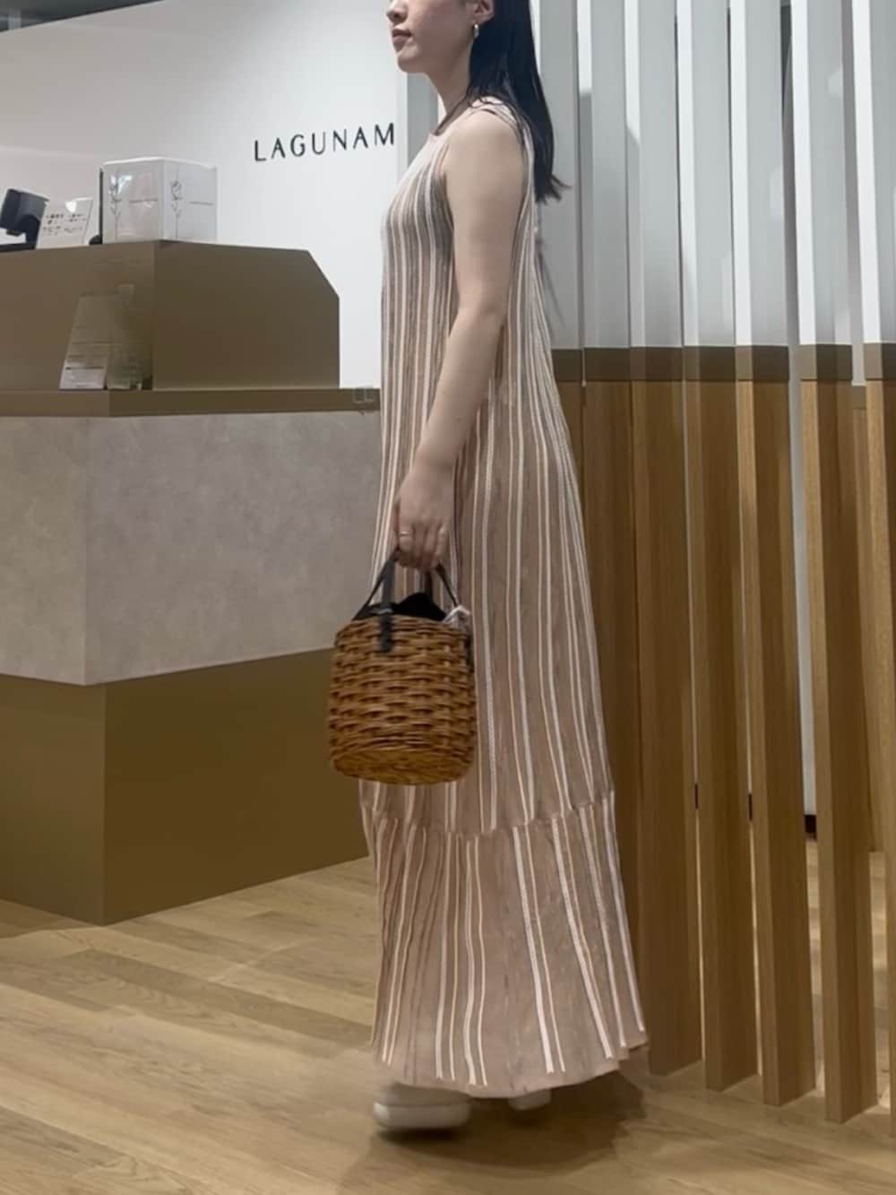 ブラウン系のハンドバッグ、オレンジ系のワンピース、ホワイト系のサンダルを着用したレディースの春コーディネートの2枚目の写真