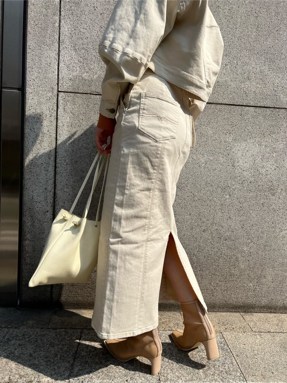 ホワイト系のブルゾン、ホワイト系のスカート、ホワイト系のハンドバッグを着用したレディースの春コーディネートの10枚目の写真