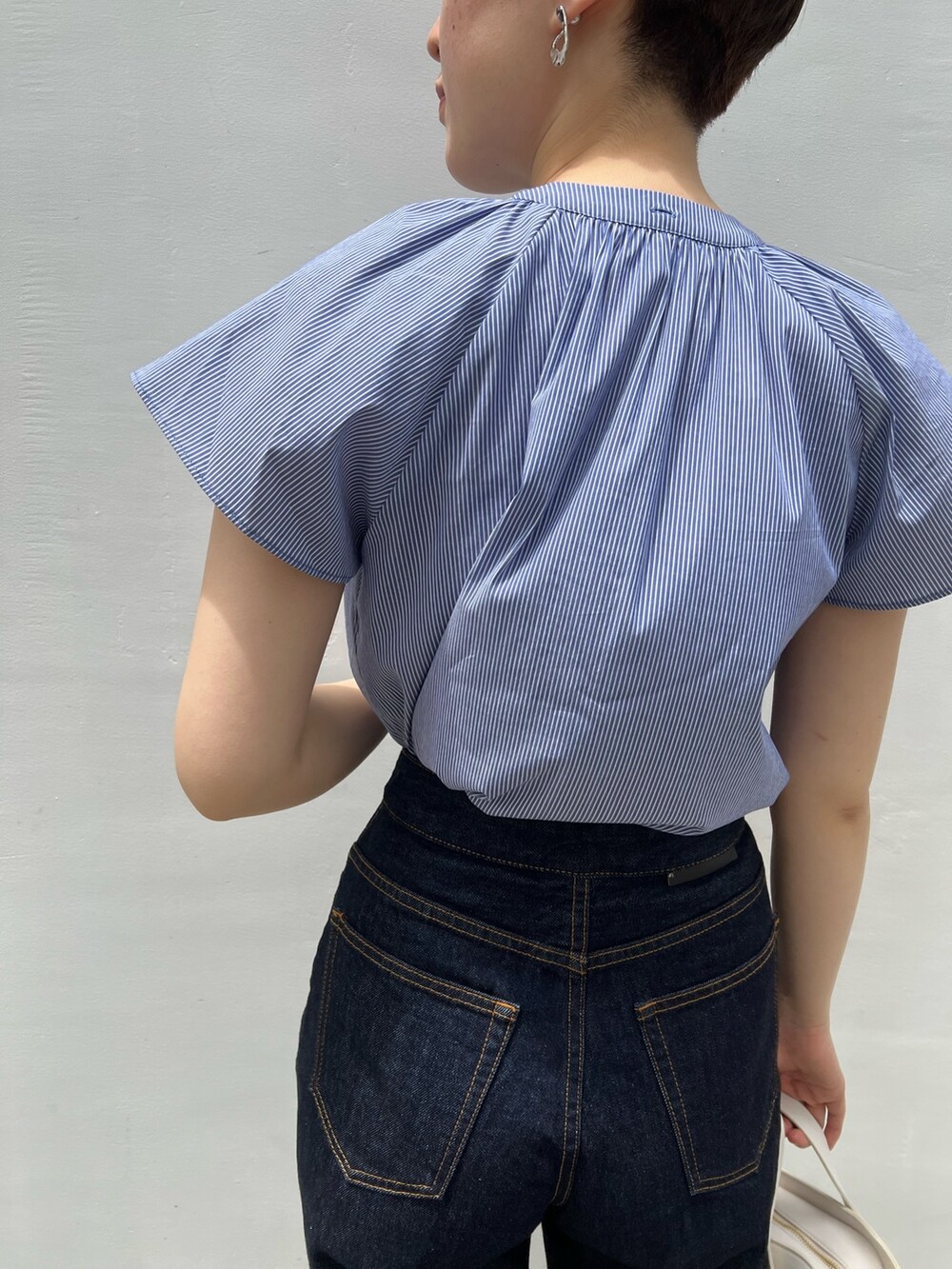 ベージュ系のサンダル、ホワイト系のショルダーバッグ、ブルー系のデニムパンツを着用したレディースの夏コーディネートの8枚目の写真