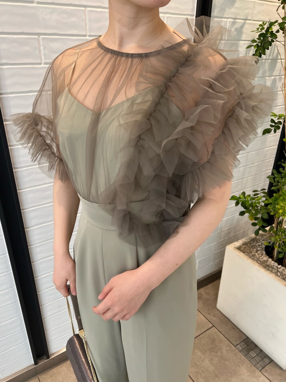 シルバー系のパンプス、シルバー系のハンドバッグ、グリーン系のパンツドレスを着用したレディースの春コーディネートの7枚目の写真