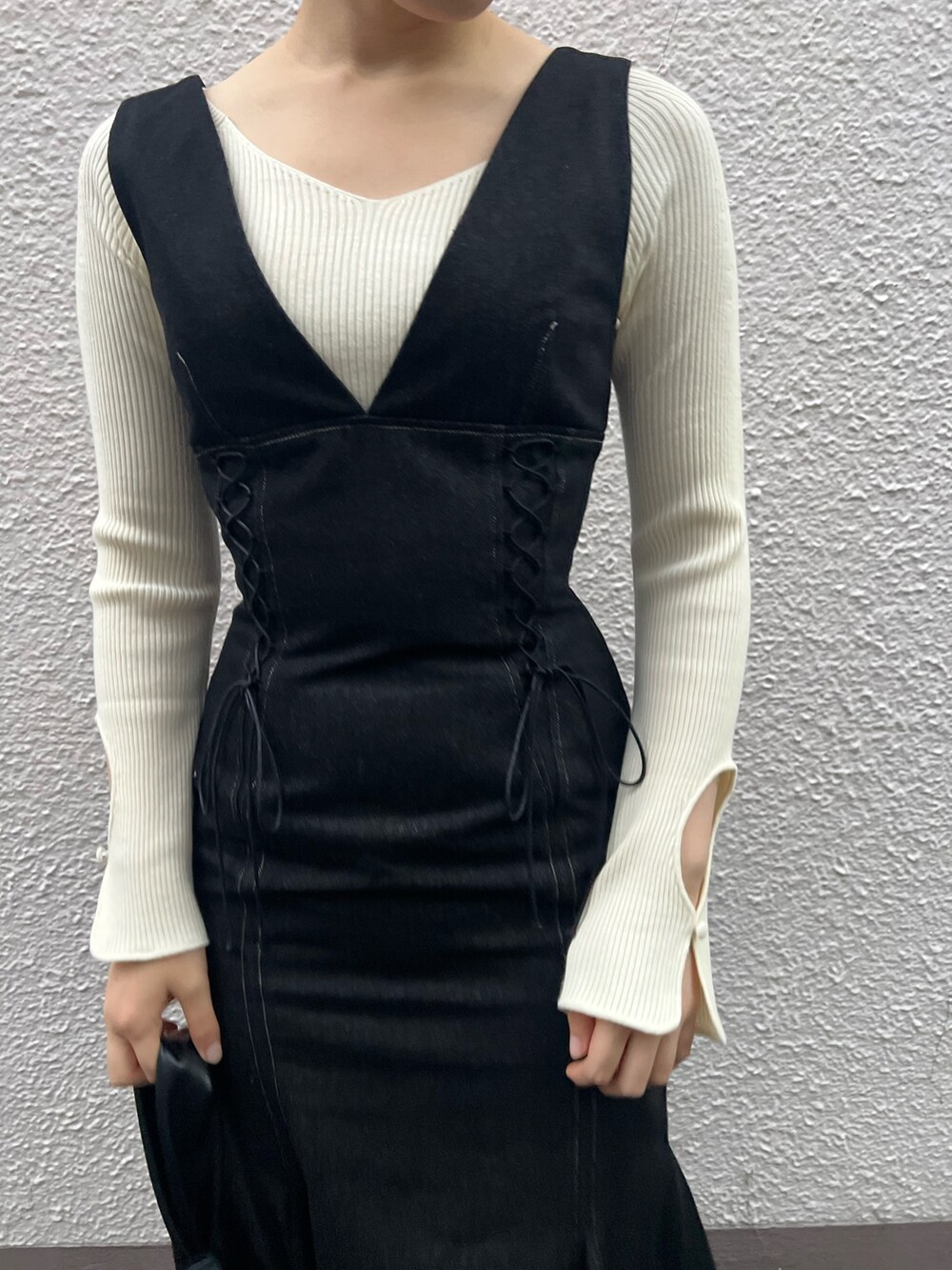 ブラック系のハンドバッグ、ブラック系のワンピース、ホワイト系のニット/セーターを着用したレディースの秋コーディネートの5枚目の写真