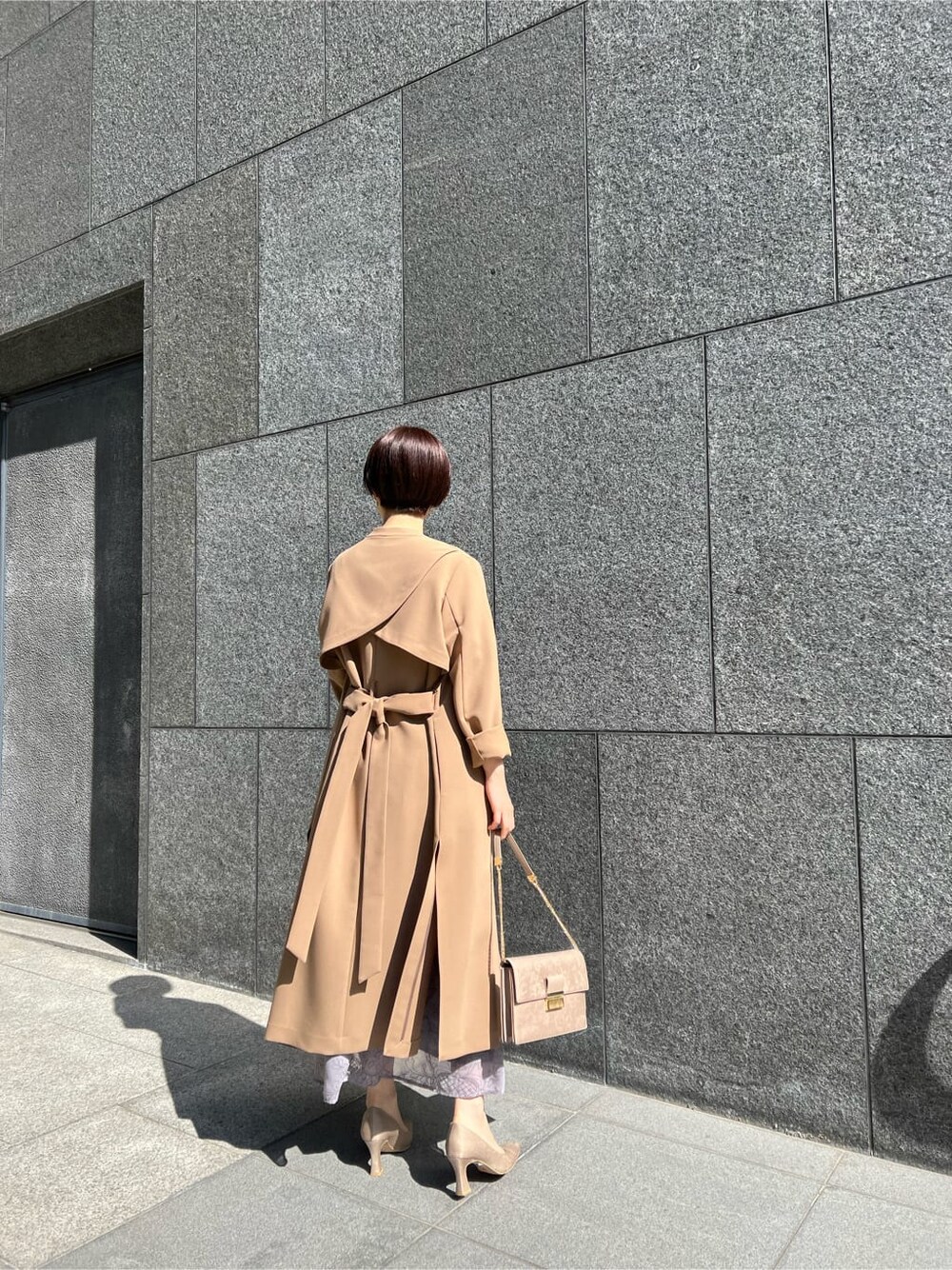 ブラウン系のクラッチバッグ、ベージュ系のその他アウター、パープル系のドレスを着用したレディースの冬コーディネートの5枚目の写真