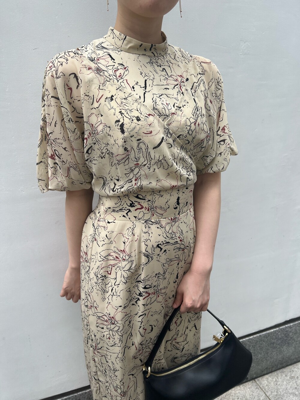 ブラック系のハンドバッグ、その他のサンダル、ベージュ系のワンピースを着用したレディースの夏コーディネートの3枚目の写真