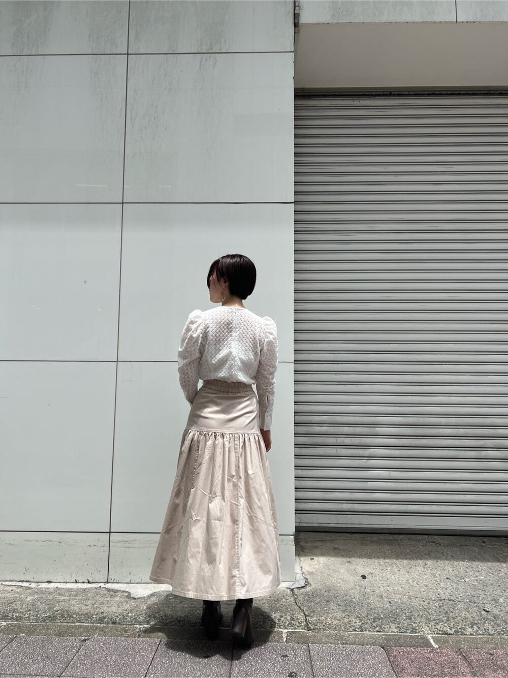 ベージュ系のスカート、ホワイト系のシャツ/ブラウス、シルバー系のピアス（両耳用）を着用したレディースの夏コーディネートの3枚目の写真