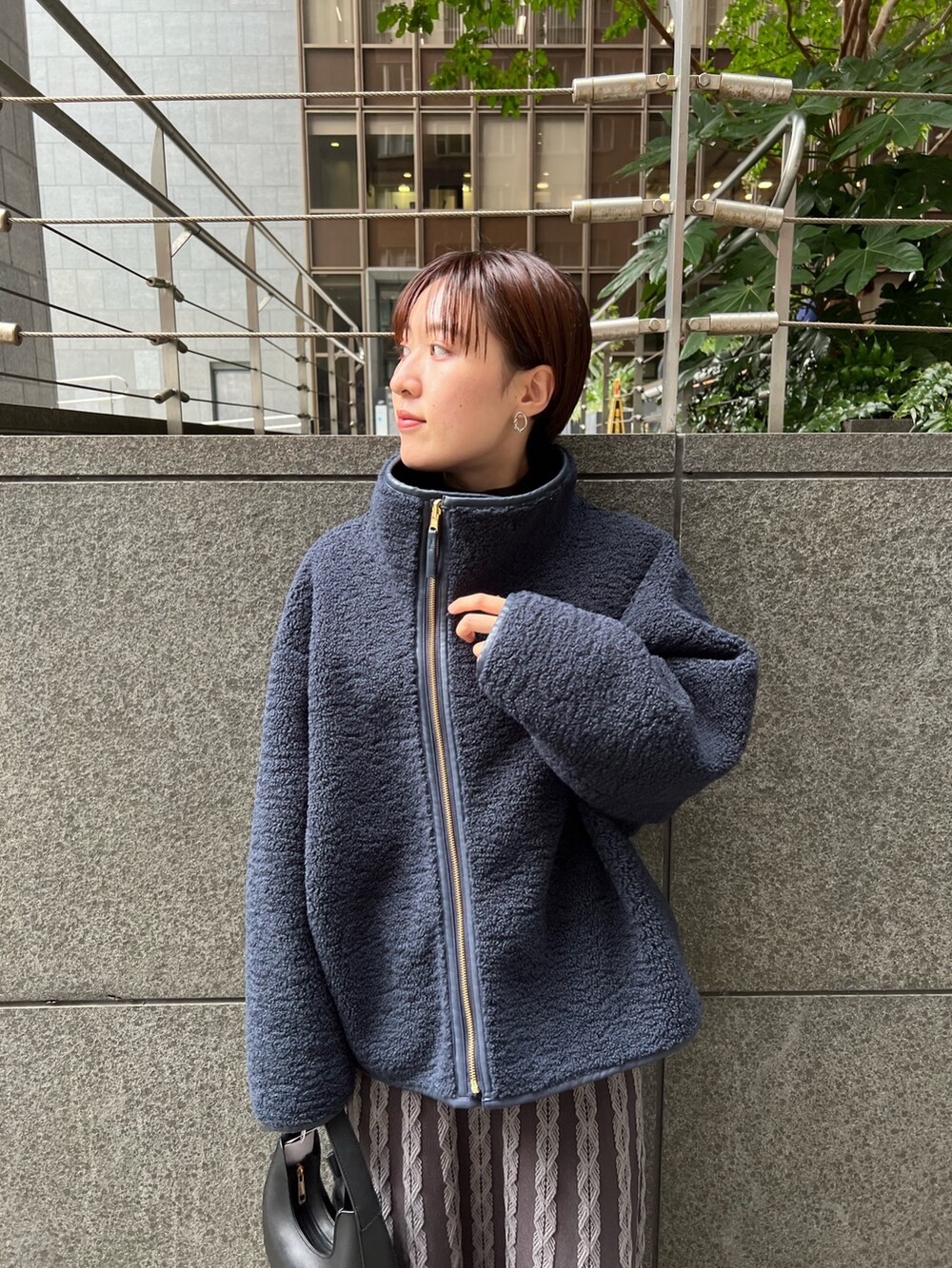 ベージュ系のブーツ、ブラック系のハンドバッグ、ブルー系のムートンコートを着用したレディースの秋コーディネートの4枚目の写真