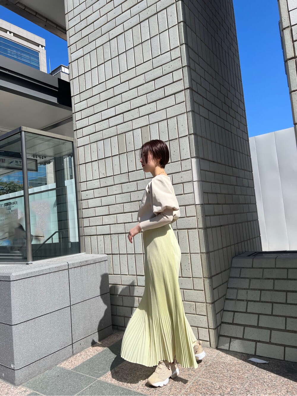 ブルー系のブルゾン、イエロー系のスカート、ベージュ系のニット/セーターを着用したレディースの春コーディネートの3枚目の写真