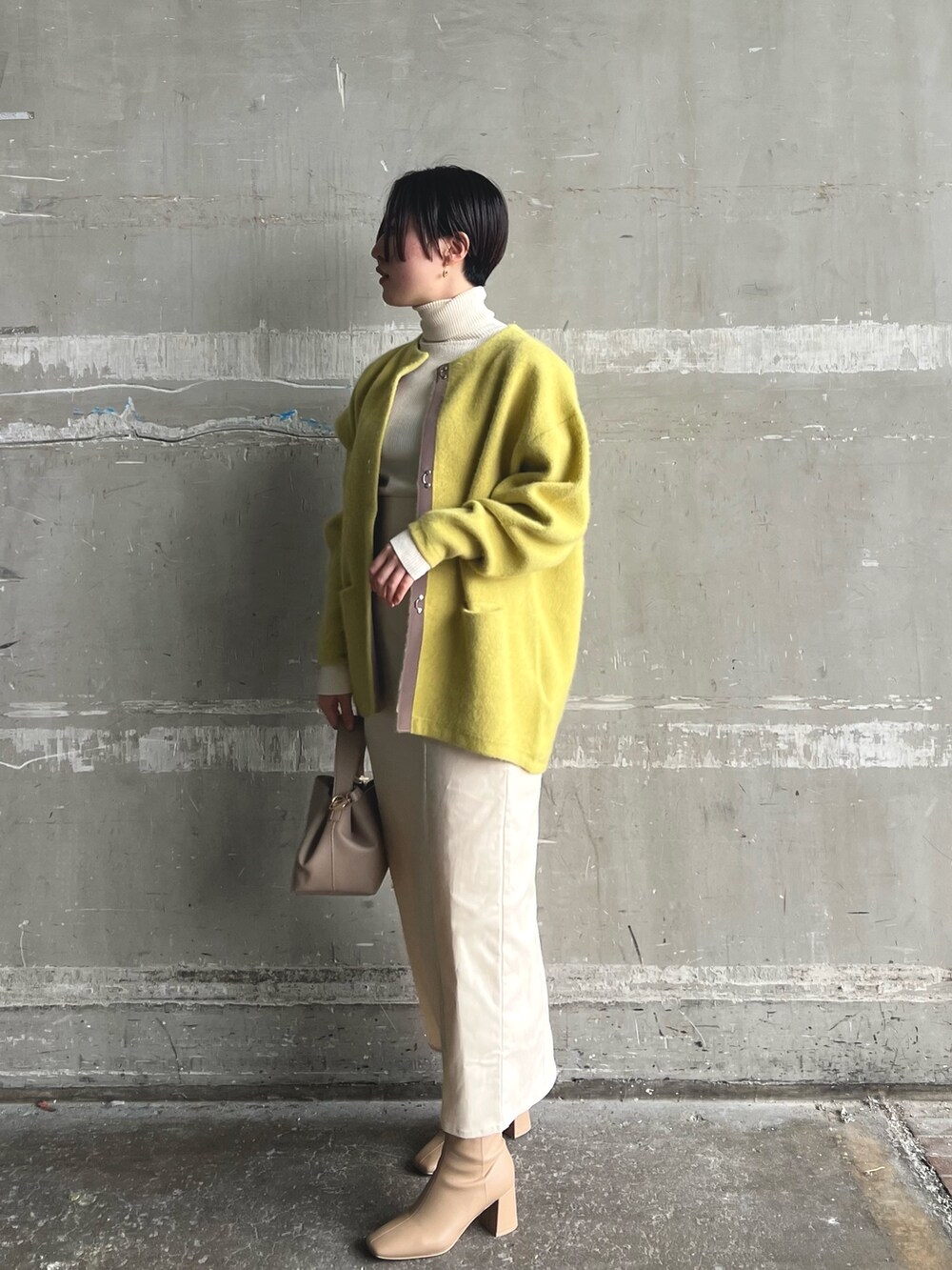 イエロー系のカーディガン/ボレロ、ベージュ系のブーツ、ホワイト系のニット/セーターを着用したレディースの秋コーディネートの2枚目の写真