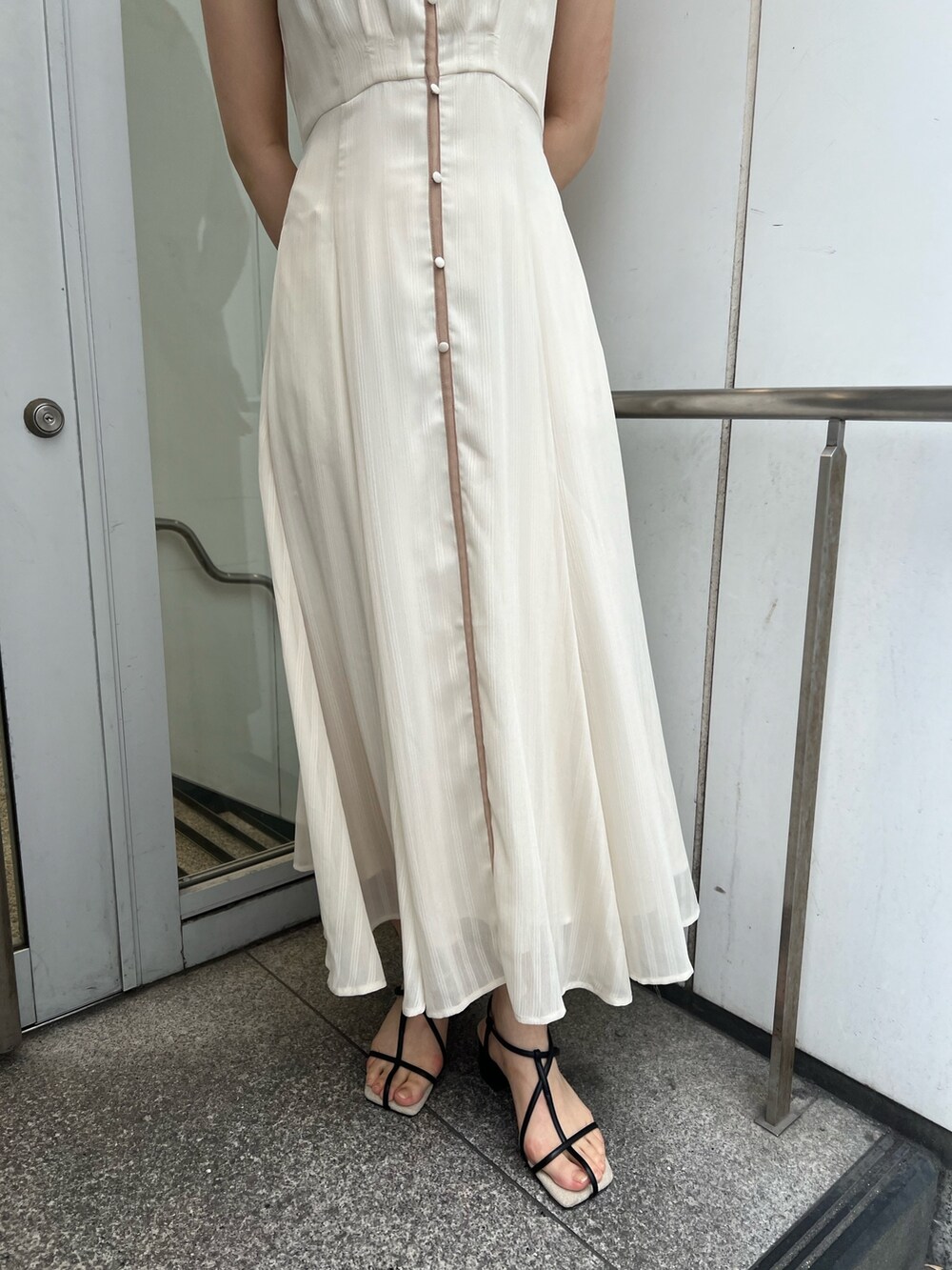 ブラック系のサンダル、ホワイト系のワンピースを着用したレディースの夏コーディネートの5枚目の写真