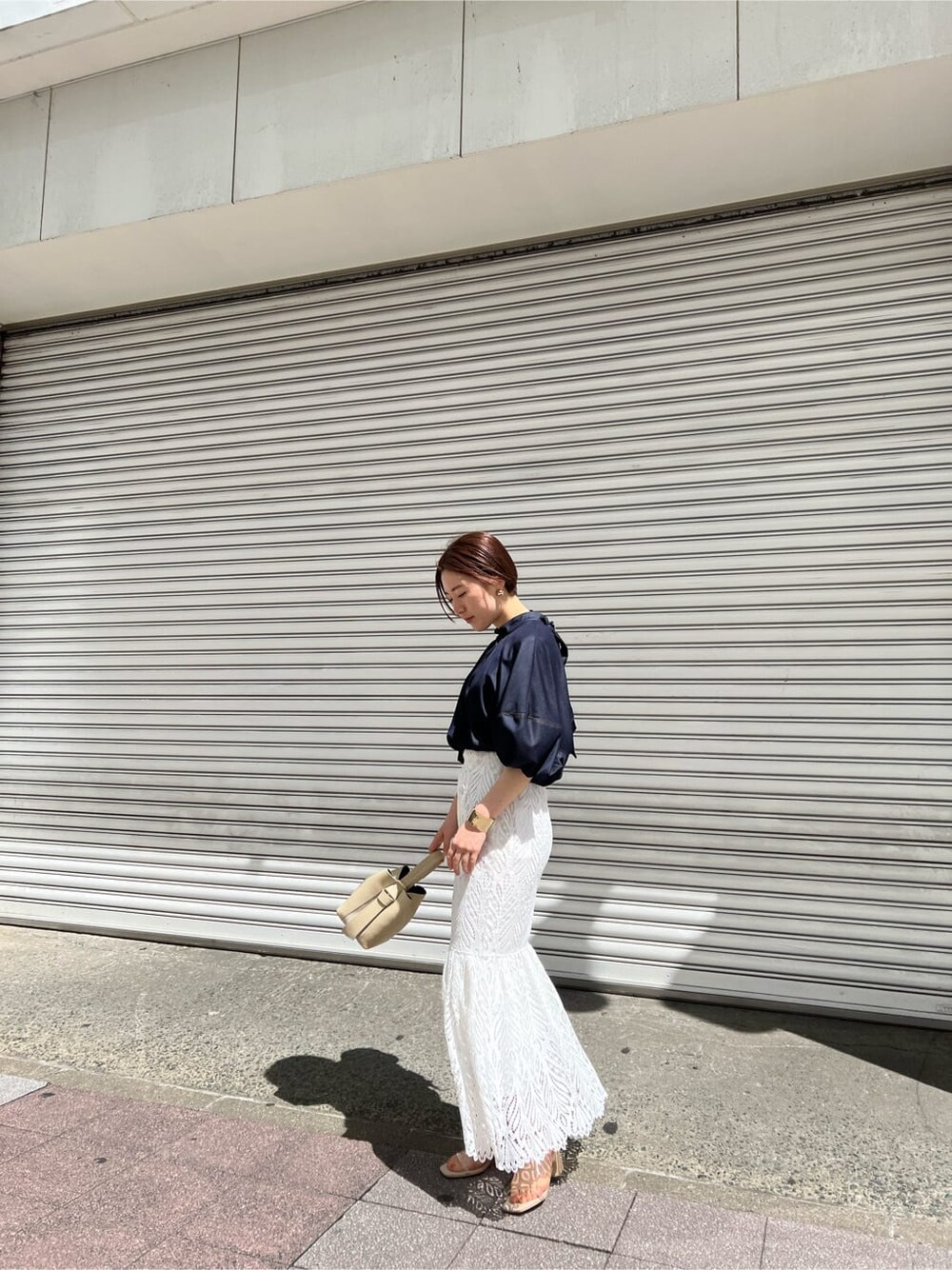 ホワイト系のハンドバッグ、ブルー系のシャツ/ブラウス、ホワイト系のスカートを着用したレディースの春コーディネートの2枚目の写真
