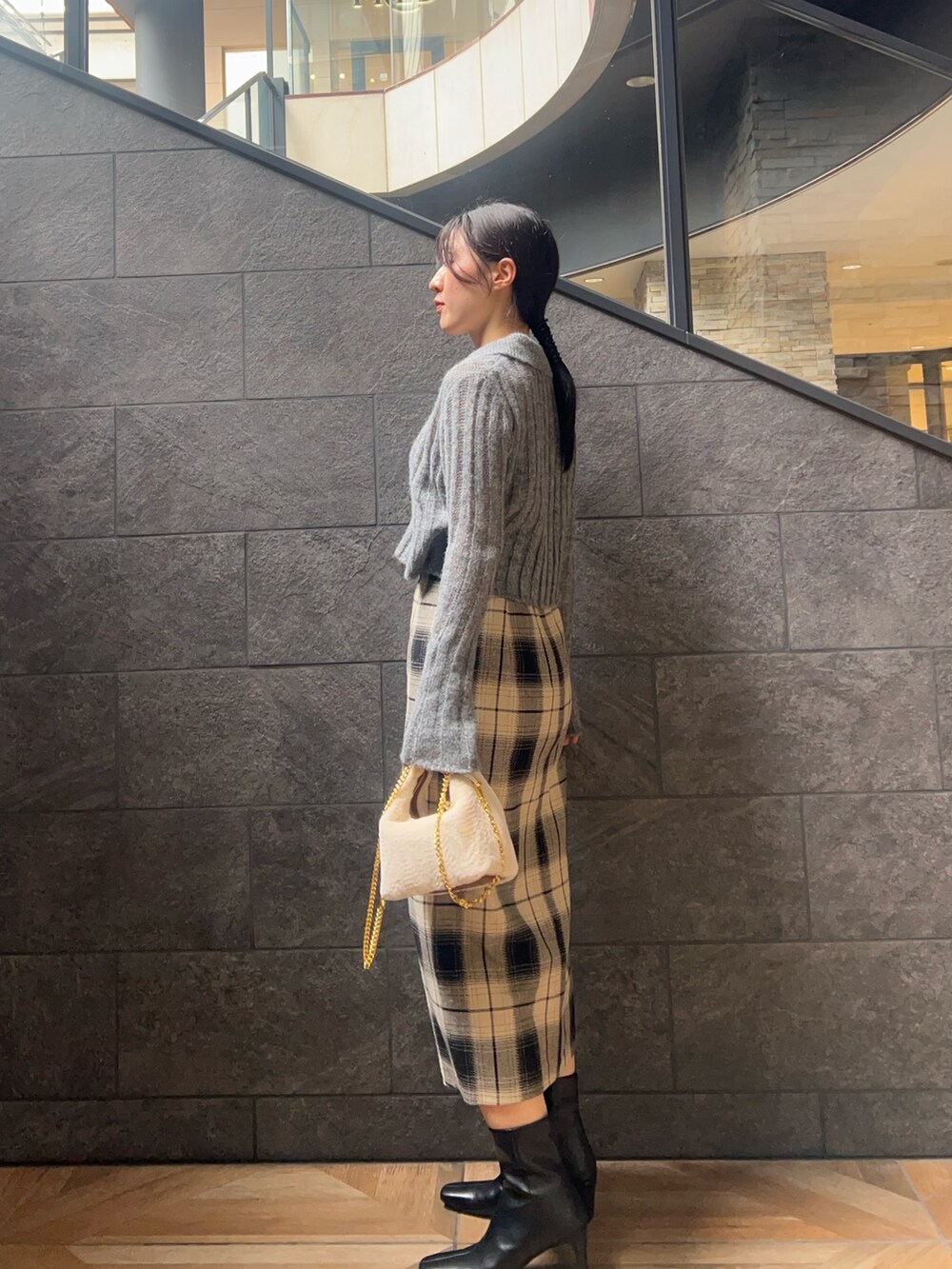 グレー系のニット/セーター、ベージュ系のスカート、ブラック系のブーツを着用したレディースの秋コーディネートの2枚目の写真