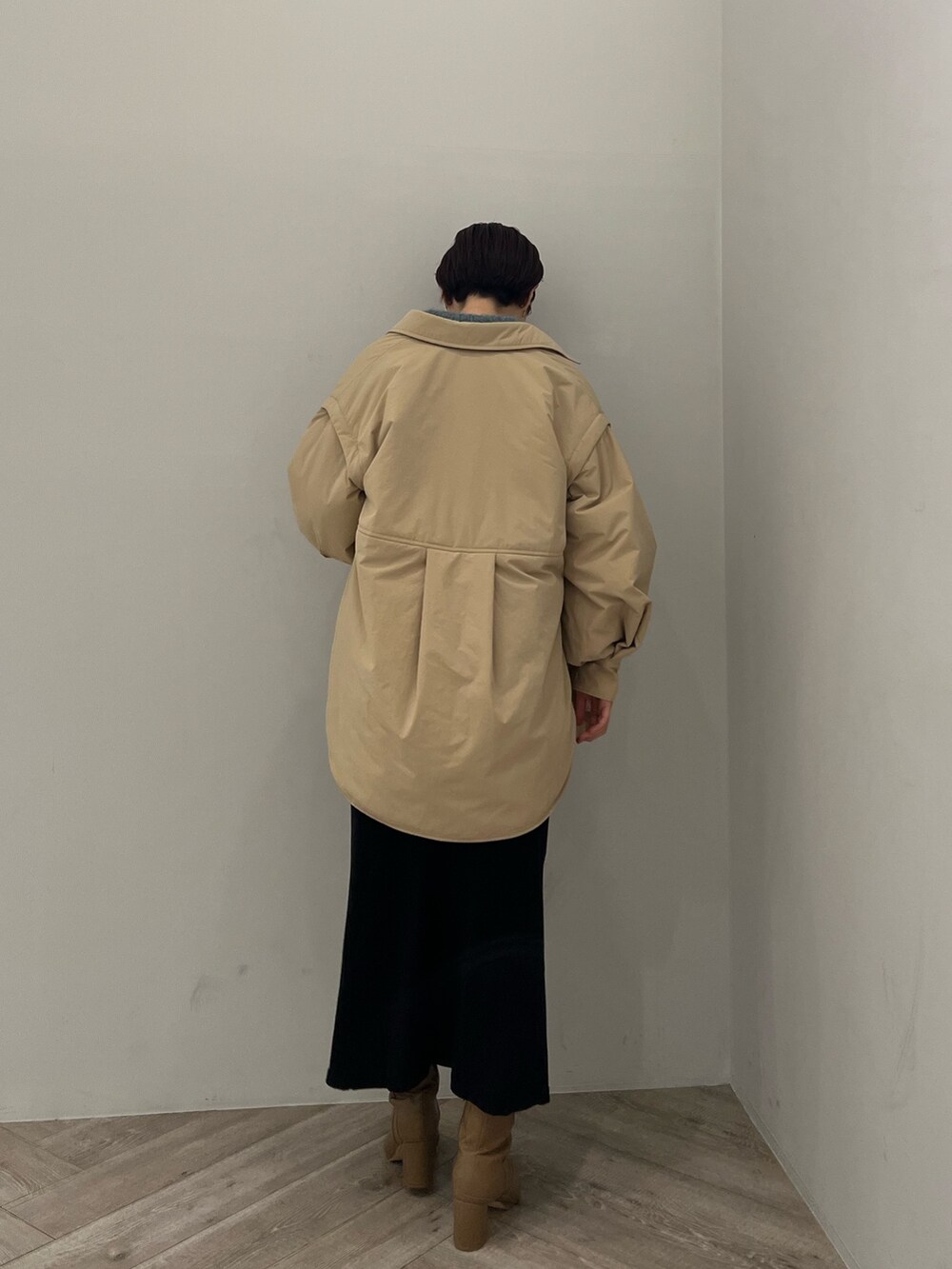 ベージュ系のブーツ、ブラック系のスカート、グリーン系のニット/セーターを着用したレディースの冬コーディネートの2枚目の写真