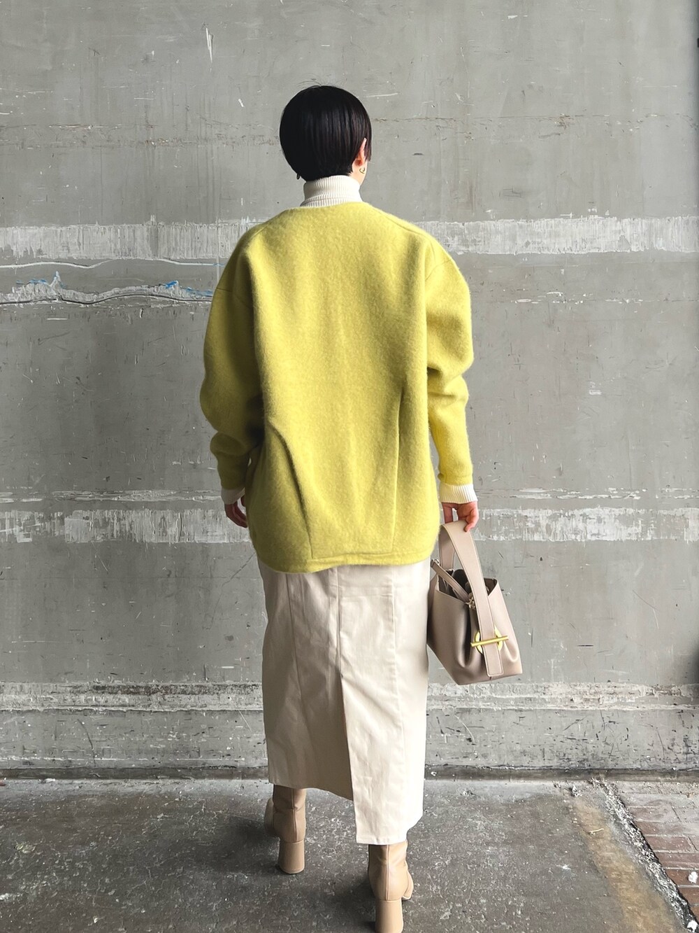 イエロー系のカーディガン/ボレロ、ベージュ系のブーツ、ホワイト系のニット/セーターを着用したレディースの秋コーディネートの3枚目の写真