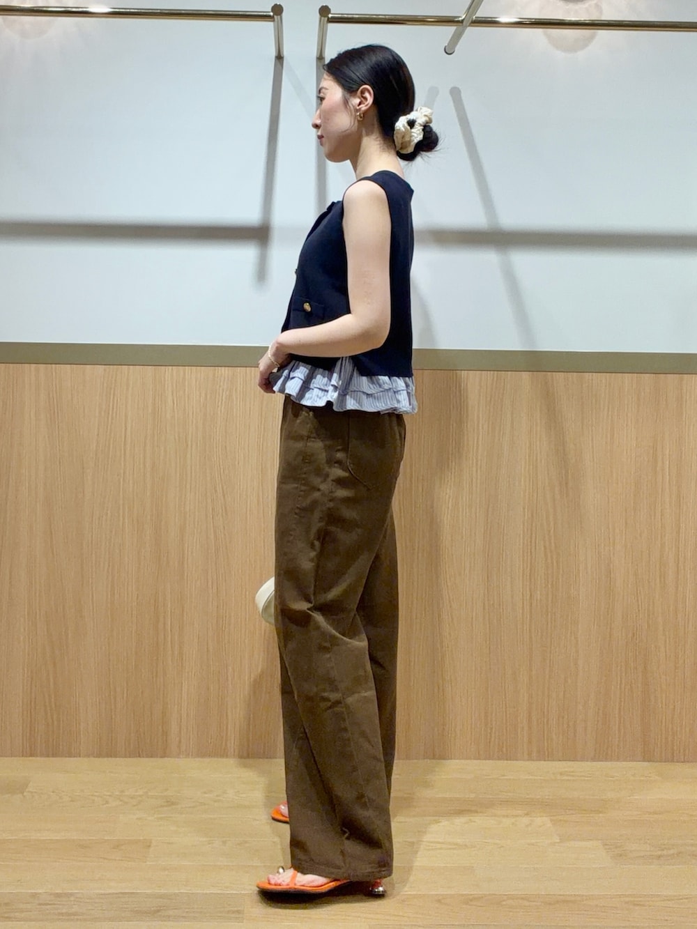 ブルー系のニット/セーター、ブラウン系のデニムパンツ、オレンジ系のサンダルを着用したレディースの夏コーディネートの2枚目の写真