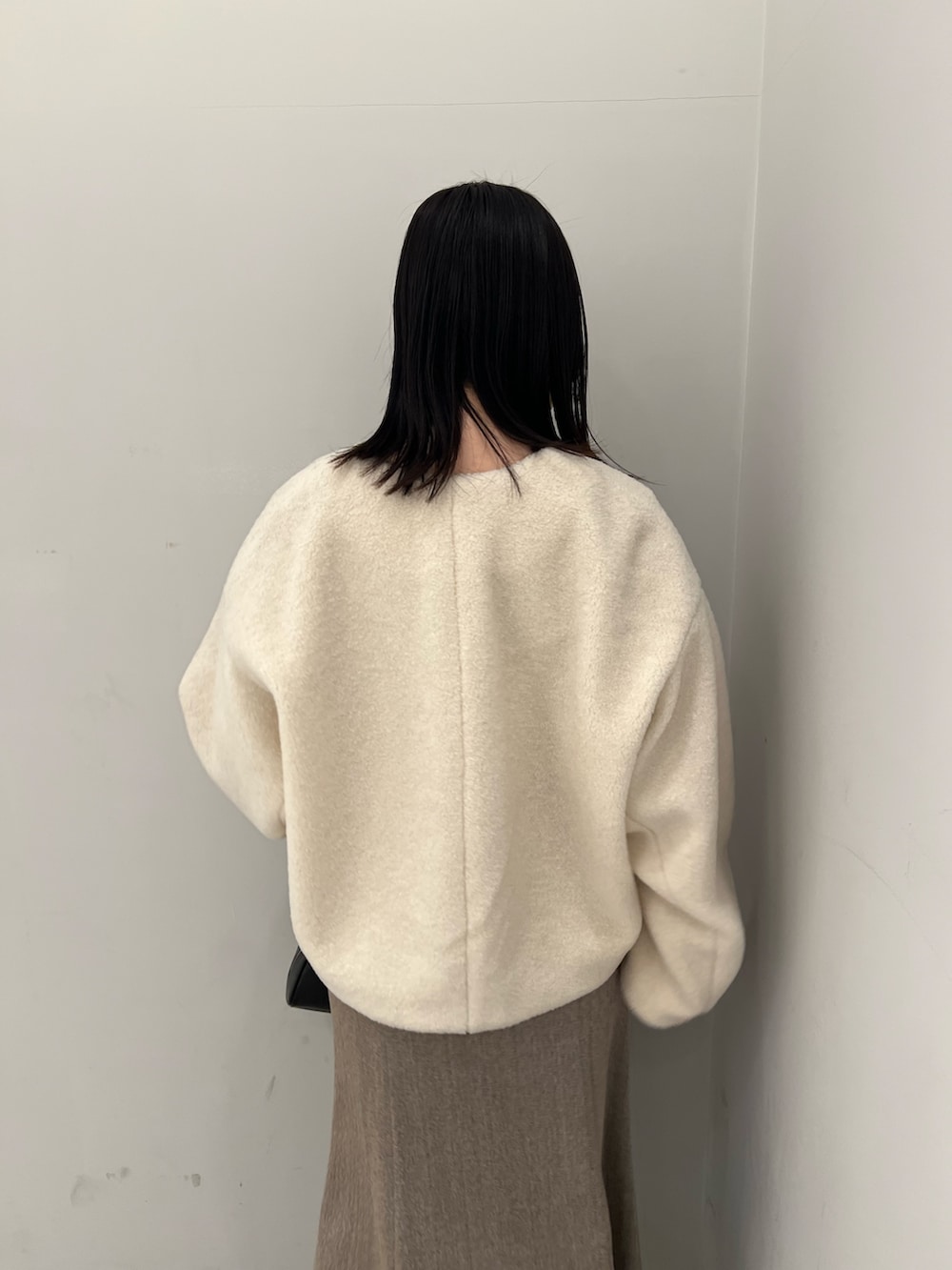 ホワイト系のブルゾン、ベージュ系のジャンパースカート、ブラック系のニット/セーターを着用したレディースの冬コーディネートの6枚目の写真